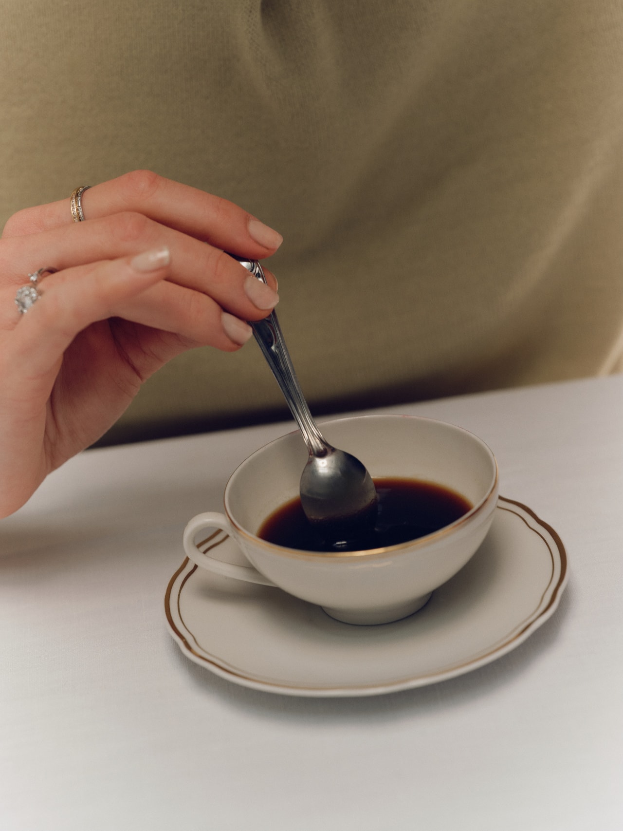 Hand rührt mit einem Löffel in einer Tasse Kaffee